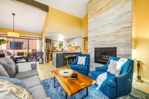 A modern living room with a sofa, armchairs, and a coffee table. There is a kitchen in the background with a fireplace. - Quiet condo near Sabino Canyon with pool, hot tub, tennis & amazing views (Tucson)