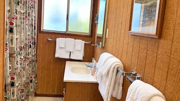 A bathroom with a wooden vanity, a sink, a mirror, and a window.