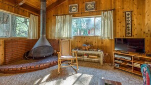 A cozy cabin interior with a fireplace, wooden walls, a television, and a comfortable seating area.