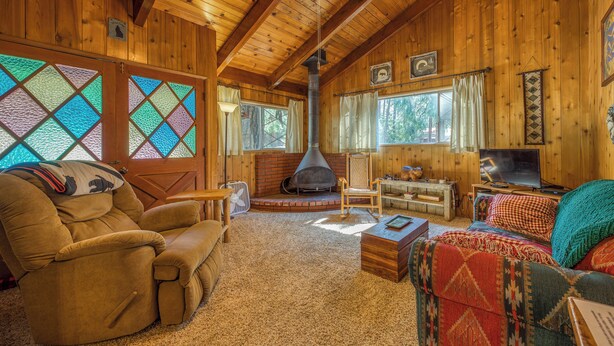 A cozy log cabin interior with a fireplace, wooden walls, and a comfortable seating area.