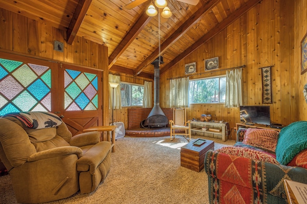 L’intérieur d’un chalet confortable, avec une cheminée, des murs en bois et un coin salon accueillant.