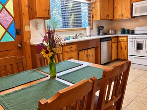 Una cocina con armarios de madera, encimera blanca, estufa y ventana con persianas.