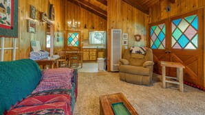 A cozy wooden cabin interior with a living room, dining area, and kitchen.