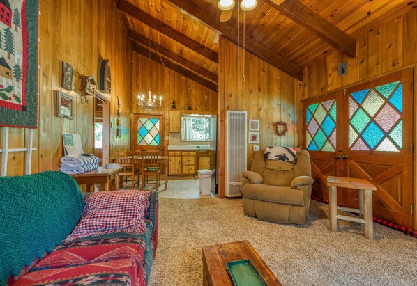 L’intérieur d’un chalet en bois chaleureux et accueillant, comprenant un salon, un coin repas et une cuisine.