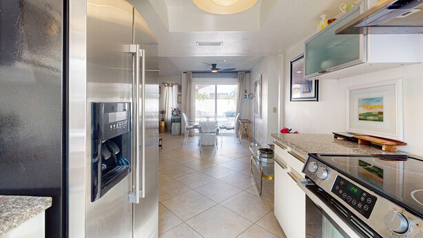 A modern kitchen with stainless steel appliances, a built-in oven, and a dining area with a glass table and chairs. - Recently Updated Home w/ Private Patios: 15 Mins From Downtown Palm Springs (Desert Hot Springs)