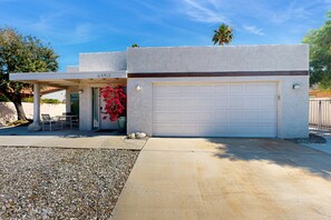 Ein modernes Haus mit Garage, überdachter Terrasse und einem Schotterweg.