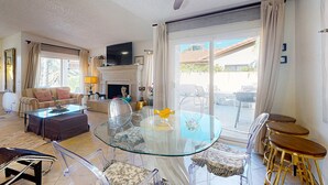 A spacious living room with a glass coffee table, clear chairs, a sofa, and a fireplace. - Recently Updated Home w/ Private Patios: 15 Mins From Downtown Palm Springs (Desert Hot Springs)