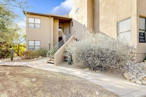 A building with a beige exterior, a staircase leading to a door, and a sign indicating it's for sale. - Dog-friendly mountain view condo with pool, hot tub, fitness room, & game room (Tucson)
