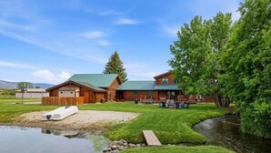 A log cabin with a green roof, a small pond, and a picnic area with chairs. - Heber Gathering Lodge, Game Room, Sleeps 32 (Heber City)