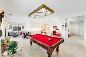A spacious living area with a pool table, a sofa set, and a kitchen in the background. - Inviting and unique dog-friendly home with pool, pool spa, firepit, & W/D (Indio)