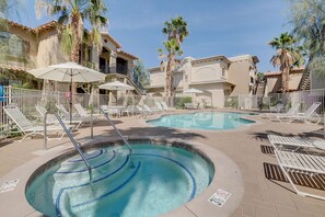 A pool area with lounge chairs, umbrellas, and a staircase leading to a building. - Clean and welcoming king-suite w/ shared pool & hot tub (La Quinta)