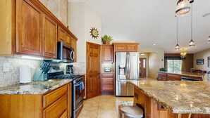 A kitchen with wooden cabinets, granite countertops, stainless steel appliances, and pendant lighting. - Luxurious Dog-Friendly home with an outdoor kitchen, private pool, spa, & casita (Bermuda Dunes)