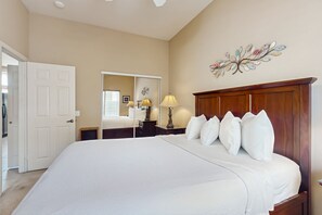 A bedroom with a large bed, a wooden headboard, a mirror, and a decorative wall piece.