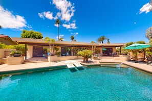 A pool area with lounge chairs and a covered seating area. - Lovely midcentury home with private pool and outdoor kitchen - dogs welcome (Bermuda Dunes)