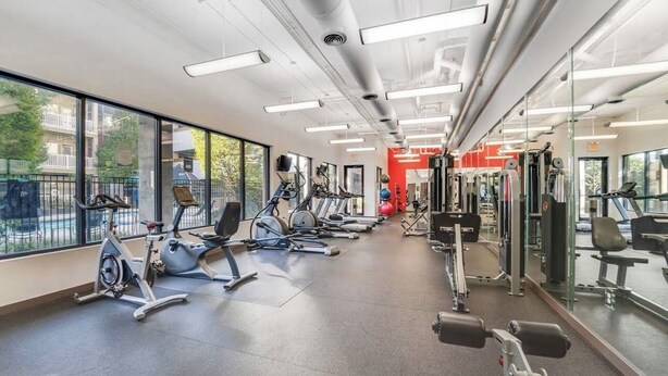 Ett gym med träningsutrustning, stora fönster och utsikt över omgivningen.