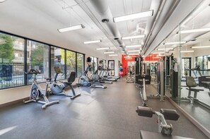 Une salle de sport équipée de matériel d’exercice, dotée de grandes fenêtres et offrant une vue sur l’extérieur.