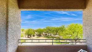 Ein Balkon mit Blick auf grüne Bäume und einen klaren Himmel.