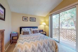 A bedroom with a bed, a nightstand, a lamp, and a view of the outdoors. - Condo with full kitchen, balconies, views of Mt. Elden - close to town (Flagstaff)