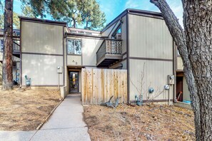 A two-story building with a wooden fence in front, a visible door, and a small balcony. - Condo with full kitchen, balconies, views of Mt. Elden - close to town (Flagstaff)