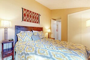 A bedroom with a patterned bedspread, a wooden headboard, a bedside lamp, and a nightstand with a clock. - Condo with full kitchen, balconies, views of Mt. Elden - close to town (Flagstaff)