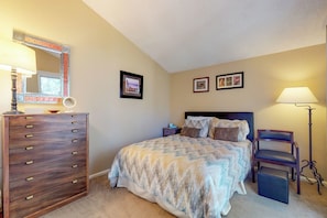 Une chambre à coucher comprenant un lit, une commode, une table de chevet, une chaise et deux tableaux encadrés accrochés au mur.