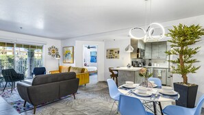 Een moderne woonkamer met een bank, eettafel en stoelen. Er is een keuken met een eettafel gedekt voor een maaltijd.