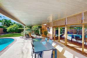 Eine Terrassenausstattung mit Pool, überdachter Essbereich und Blick auf ein Schwimmbad.