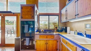 Una cocina con armarios de madera, estufa a gas y un lavamanos.