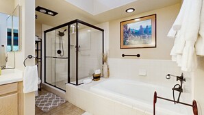 A modern bathroom with a glass-enclosed shower, a large bathtub, and a framed cityscape painting on the wall. - Beautiful Sedona townhome with pool, hot tub, tennis, & on-site golf (Sedona)