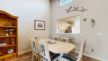 A dining area with a wooden table and chairs, a wooden cabinet, and wall decorations including a framed picture and wall art.