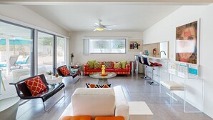 Ein modernes Wohnzimmer mit einer Couch, Sesseln, einem Couchtisch und einer Küchenzeile mit Bar.
