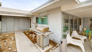 Ein modernes Haus mit Grill, Sitzgelegenheit im Freien und einer Terrassenfläche.