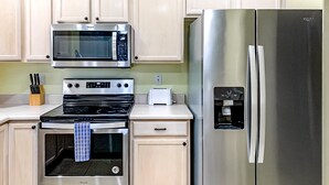 A kitchen with a stainless steel refrigerator, a microwave, an oven, and a toaster. - Bright & modern resort condo with pool & hot tub (Oro Valley)
