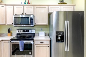 A kitchen with a stainless steel refrigerator, a microwave, an oven, and a toaster. - Bright & modern resort condo with pool & hot tub (Oro Valley)