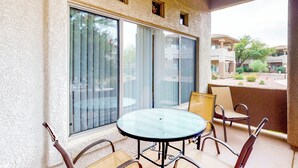 A balcony with a glass door, a round table, and four chairs. - Bright & modern resort condo with pool & hot tub (Oro Valley)