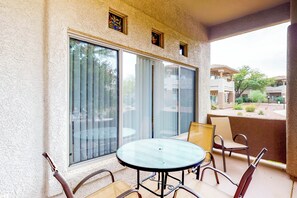 A balcony with a glass door, a round table, and four chairs. - Bright & modern resort condo with pool & hot tub (Oro Valley)