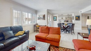 A living room with a sofa, a coffee table, and a dining area with chairs and a table. - Dog-friendly condo w/ balcony & shared pools/hot tubs - close to downtown (Palm Springs)