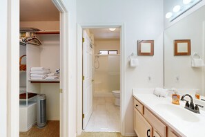 A bathroom with a white sink, mirror, and towel rack. There is a shower area visible through an open door. - Stylish condo with pool, hot tub & lovely mountain views (Oro Valley)