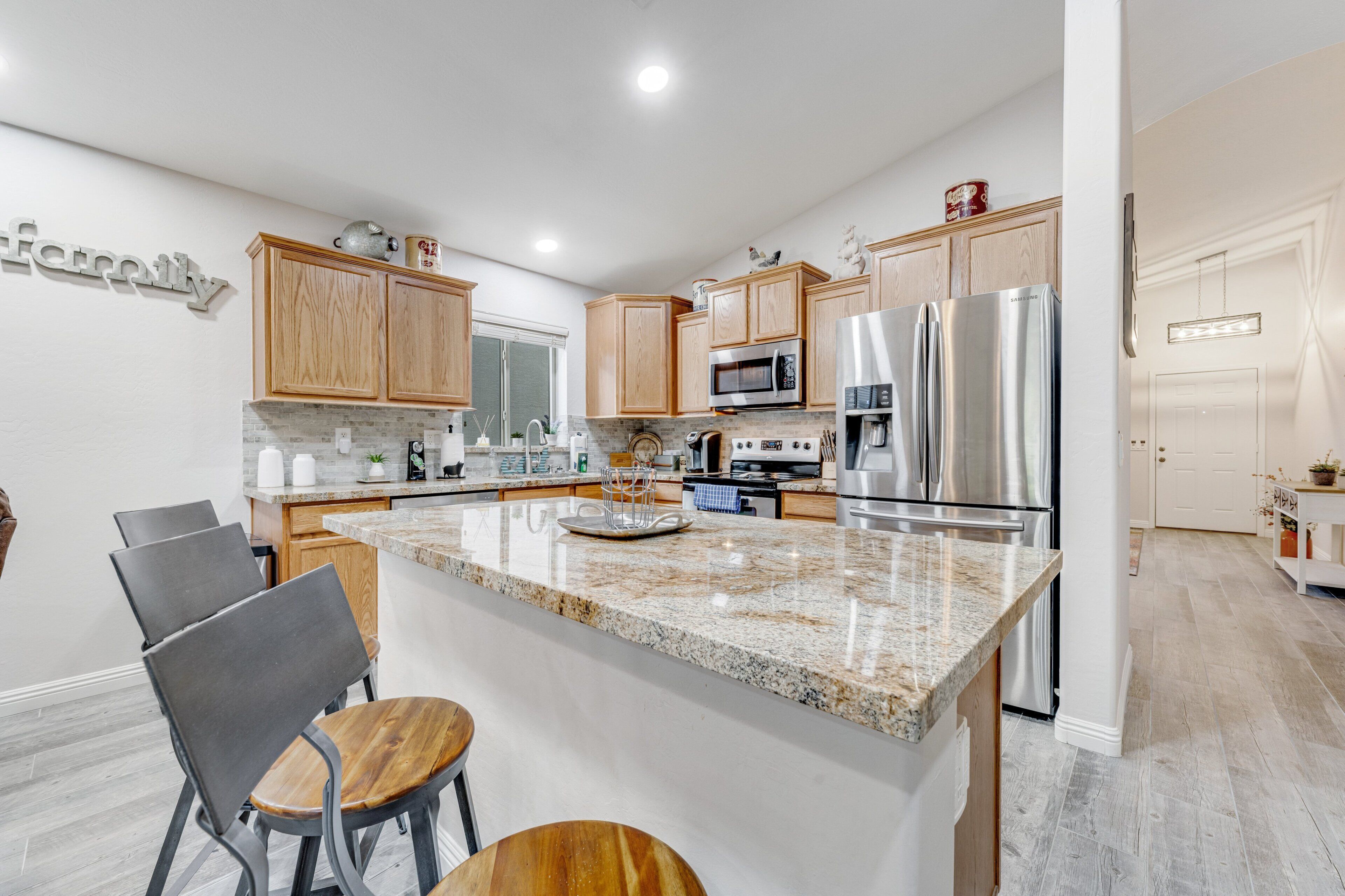 A modern kitchen with wooden cabinets, stainless steel appliances, and a granite countertop.