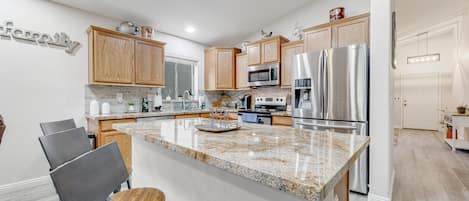 A modern kitchen with wooden cabinets, stainless steel appliances, and a granite countertop.