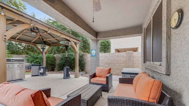 An outdoor patio area with wicker furniture, a grill, and a covered seating area. - Dreamy home with private pool, high-speed WiFi, full kitchen, & W/D (Sun City)