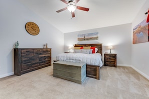 Ein Schlafzimmer mit Bett, Schminktisch, Nachttischen, einer Uhr und einem Deckenventilator.