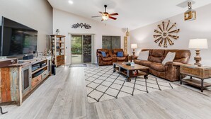A spacious living room with a large flat-screen TV, leather sofas, a coffee table, and a wooden entertainment unit. - Dreamy home with private pool, high-speed WiFi, full kitchen, & W/D (Sun City)