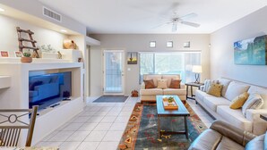 A living room with a TV, sofa, coffee table, and decorative items. - Spacious condo with pools, hot tub, patio & lovely views - dog-friendly (Oro Valley)