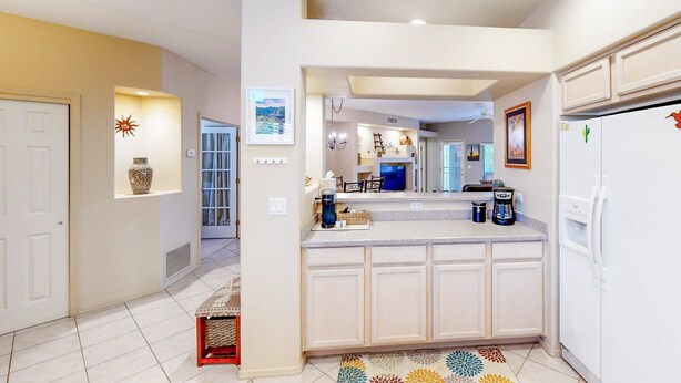 A kitchen with white cabinets, a refrigerator, a coffee maker, and a microwave. - Spacious condo with pools, hot tub, patio & lovely views - dog-friendly (Oro Valley)