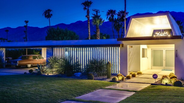 A modern house with a driveway, parked cars, and a well-maintained lawn. - Cheerful mid-century home w/ private pool, spa, firepit & mountain views (Palm Springs)