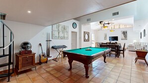 Ein geräumiger Wohnbereich mit Billardtisch, Gitarre und Esstisch mit Stühlen.