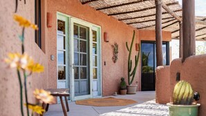A covered patio area with a cactus, a wooden table, and a door with green shutters. - 3 Bedroom with Pool & Mountain Views (Los Barriles)