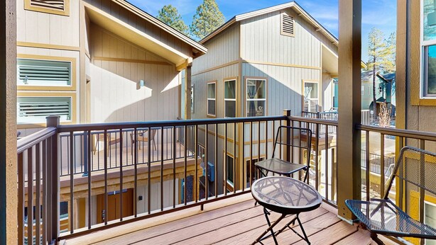 A wooden deck with a railing, a table, and chairs. - Modern, dog-friendly bungalow home with patio, balcony, & central AC (Flagstaff)
