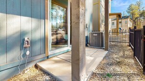 A residential building with a covered porch, a visible air conditioning unit, and a clear view of the surrounding neighborhood. - Modern, dog-friendly bungalow home with patio, balcony, & central AC (Flagstaff)